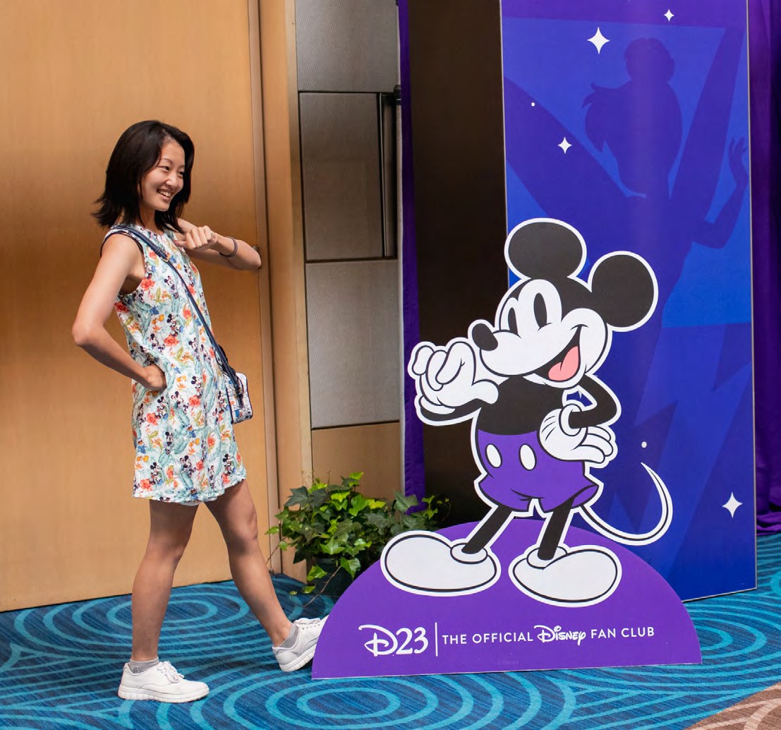 Destination D23 environmental and stage design for the Disney100 celebration, including custom character illustrations in Disney100 purple
