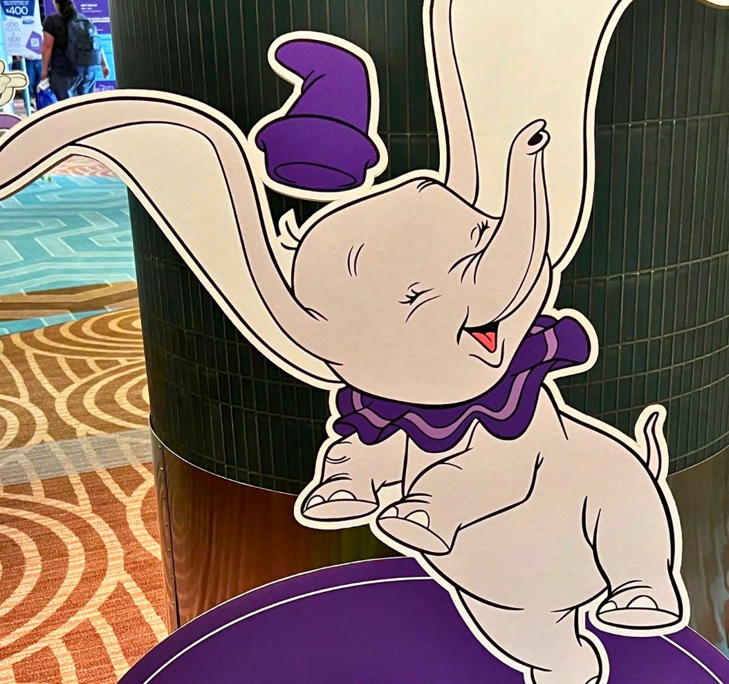 Destination D23 environmental and stage design for the Disney100 celebration, including custom character illustrations in Disney100 purple